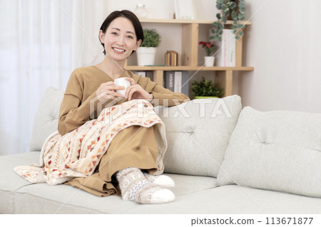 Woman relaxing in the living room, warming up, poor circulation Woman relaxing in the living room, warming up, poor circulation 113671877