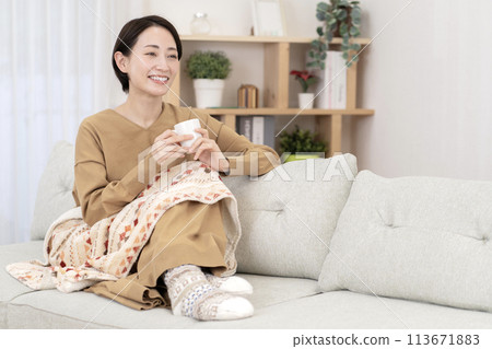 一個女人在客廳放鬆，溫暖而對寒冷敏感 113671883