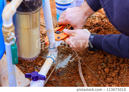 Plumber cuts plastic PVC pipe using special pair of scissors Plumber cuts plastic PVC pipe using special pair of scissors 113673018