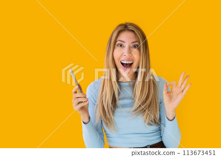 Portrait of a young Caucasian woman with pleasant smile isolated on yellow wall with copy space.  113673451