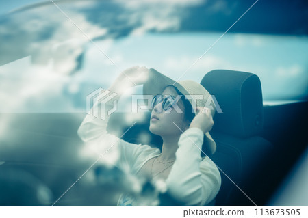 Woman looking at the ocean from the window of an open car Woman looking at the ocean from the window of an open car 113673505