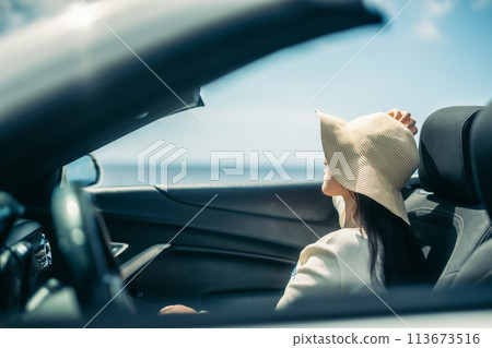 Woman looking at the ocean from the window of an open car Woman looking at the ocean from the window of an open car 113673516