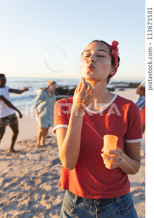 Young Caucasian woman blows bubbles on a sunny beach 113673581