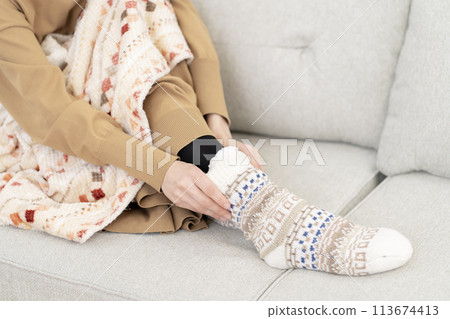 Woman wearing room socks, cold, body parts, part cut, no face 113674413
