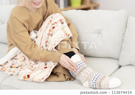 Woman wearing room socks, cold, body parts, part cut, no face 113674414