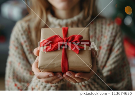 Woman hands holding the gift, presenting the box with bow. 113674650