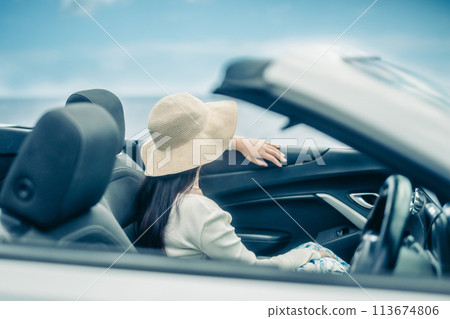 Woman looking at the ocean from the window of an open car 113674806
