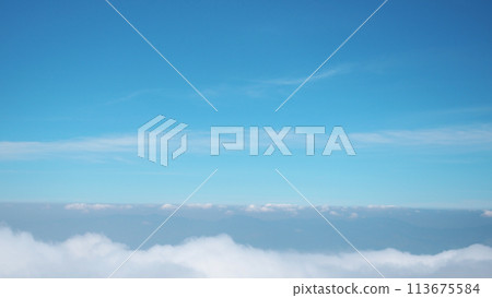 Sea of clouds view from a mountain peak against a background of a blue sky. 113675584