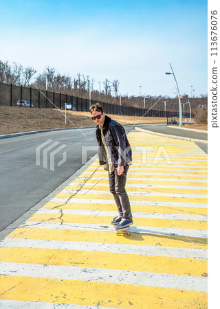 Young man riding a skateboard on a pedestrian cross road Young man riding a skateboard on a pedestrian cross road 113676076