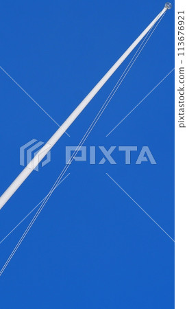 Aminimalist picture of Single flagpole with no flag, on blue sky background 113676921
