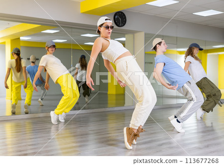 Cool active teenage girls and boy learning dance movements during group training in dance studio 113677268