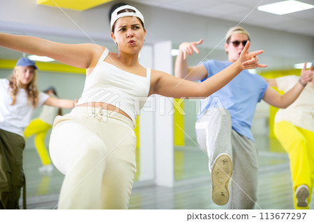 Teenage girl having group dance training in studio, performing dynamic elements 113677297