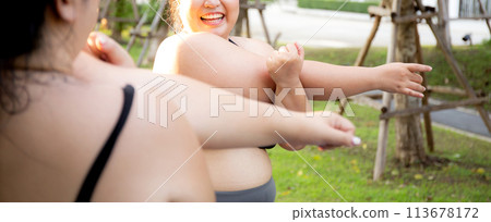 Obese two young asian woman doing stretching arm muscle in the park. 113678172