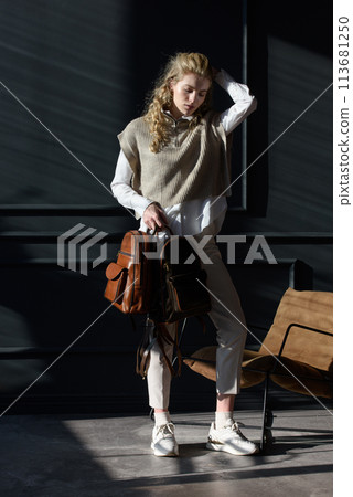 beautiful curly blond hair woman posing with a leather backpack beautiful curly blond hair woman posing with a leather backpack 113681250