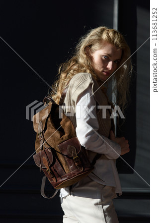 beautiful curly blond hair woman posing with a leather backpack beautiful curly blond hair woman posing with a leather backpack 113681252