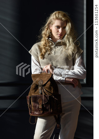 beautiful curly blond hair woman posing with a leather backpack 113681254
