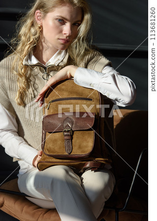 beautiful curly blond hair woman posing with a leather backpack beautiful curly blond hair woman posing with a leather backpack 113681260