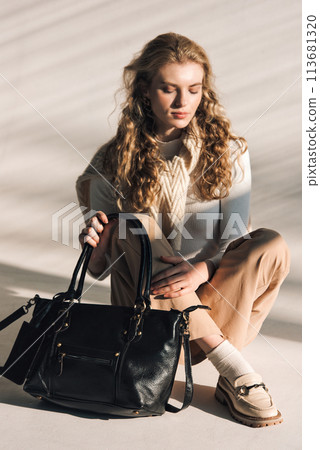 beautiful curly blond hair woman posing with a small shopper bag sitting on the floor beautiful curly blond hair woman posing with a small shopper bag sitting on the floor 113681320