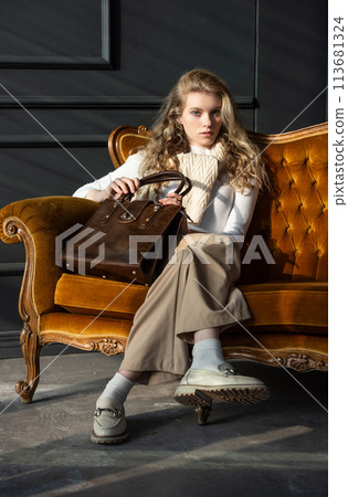 beautiful curly blond hair woman posing with a small shopper brown bag in a vintage chair beautiful curly blond hair woman posing with a small shopper brown bag in a vintage chair 113681324