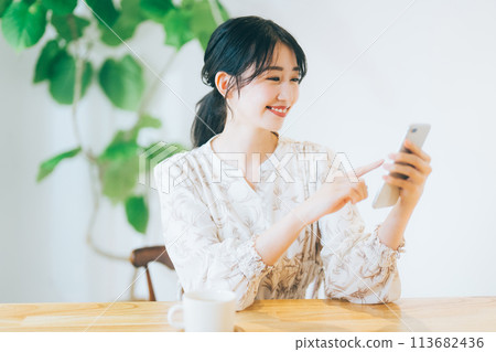 A woman looking at her smartphone in the living room 113682436