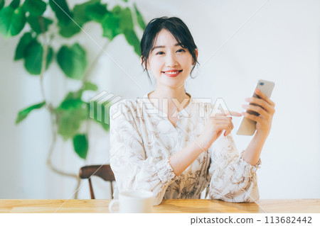 一個女人在客廳裡看著她的智能手機 113682442