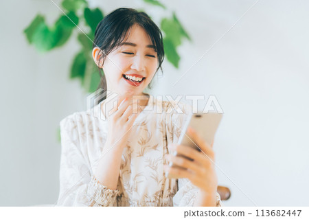 A woman looking at her smartphone in the living room A woman looking at her smartphone in the living room 113682447