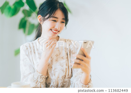 A woman looking at her smartphone in the living room 113682449