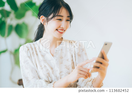 一個女人在客廳裡看著她的智能手機 113682452