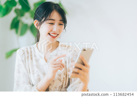 A woman looking at her smartphone in the living room 113682454