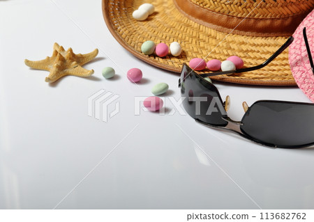Accessories for summer holidays. Sun hats, sunglasses, colored pebbles and starfish on a white background. 113682762