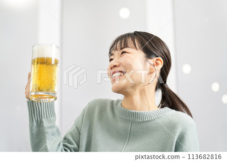 Woman drinking beer from a mug at home Woman drinking beer from a mug at home 113682816