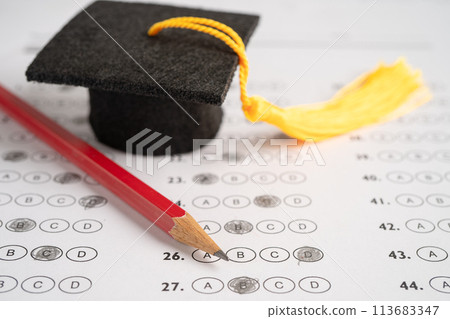 Graduation gap hat and pencil on answer sheet background, Education study testing learning teach concept. Graduation gap hat and pencil on answer sheet background, Education study testing learning teach concept. 113683347