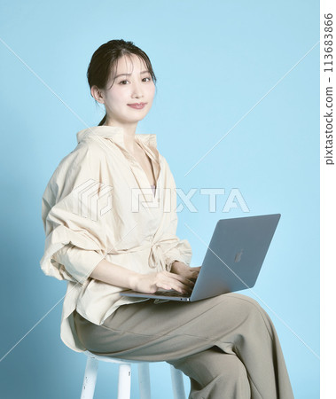 A young woman working on a PC against a blue background A young woman working on a PC against a blue background 113683866
