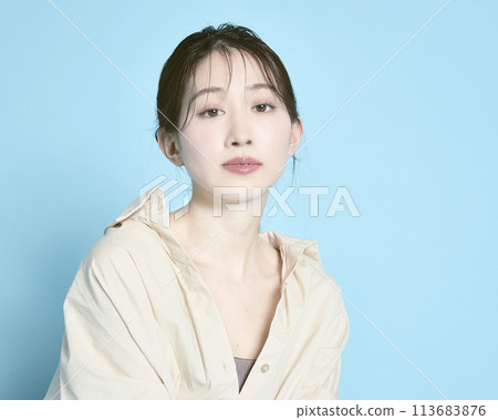 Portrait of a young woman against a blue background Portrait of a young woman against a blue background 113683876