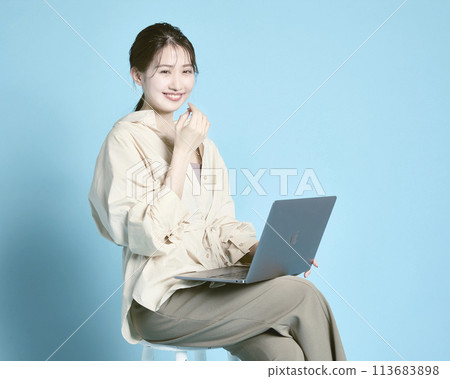 A young woman working on a PC against a blue background A young woman working on a PC against a blue background 113683898