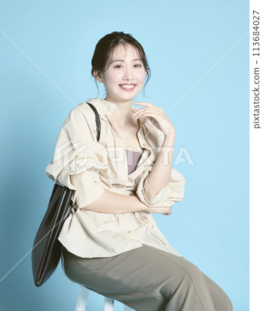 藍色背景下拎著包包的年輕女子 113684027