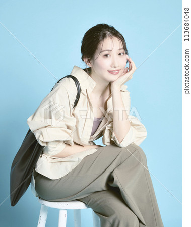 Young woman holding a bag photographed against a blue background 113684048
