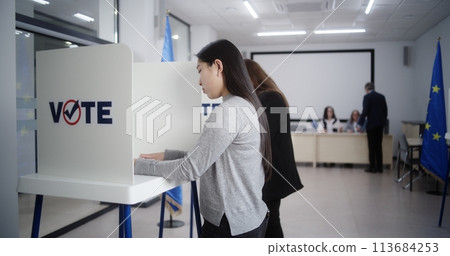 Diverse voters fill out ballots in voting booths during EU elections Diverse voters fill out ballots in voting booths during EU elections 113684253