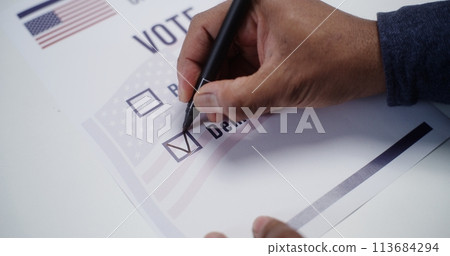 Anonymous US citizen placing paper ballot on the table 113684294