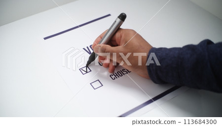 Close up of anonymous male voter filling out paper ballot during elections Close up of anonymous male voter filling out paper ballot during elections 113684300