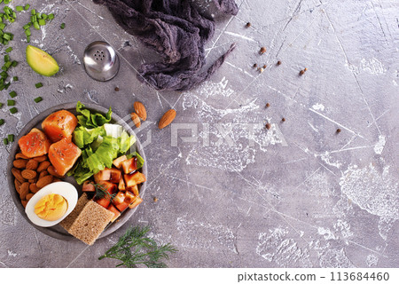 salad with salmon, boiled egg, bean, tomato, salad and almond nuts. 113684460