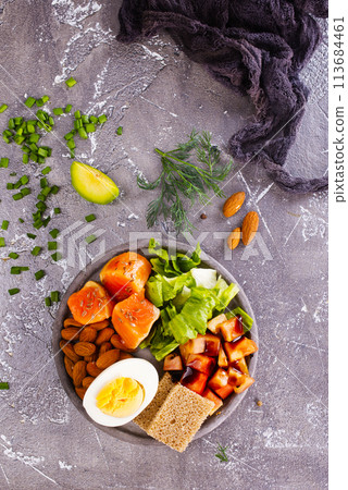 salad with salmon, boiled egg, bean, tomato, salad and almond nuts. 113684461