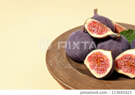 Fresh ripe figs in a wooden bowl on a light background 113685825