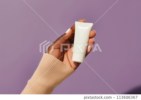 African American womans hand holds white tube on purple background. Skin health care concept 113686367