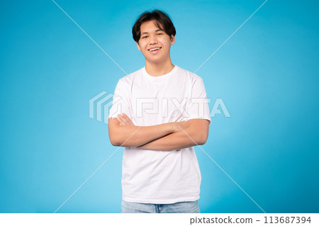 Cheerful young guy with arms crossed, blue background 113687394