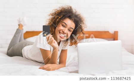 African-american woman doing online shopping in the bedroom African-american woman doing online shopping in the bedroom 113687425
