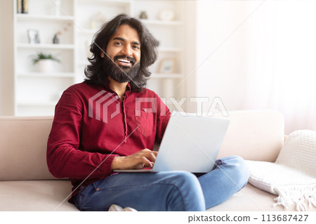 Relaxed man with laptop sitting on couch Relaxed man with laptop sitting on couch 113687427