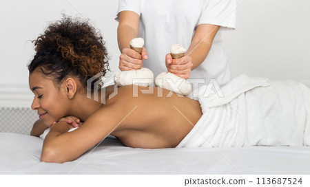 Girl having Thai herb compress massage in beauty spa 113687524