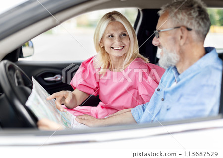 Elderly couple reading map in car, traveling together 113687529