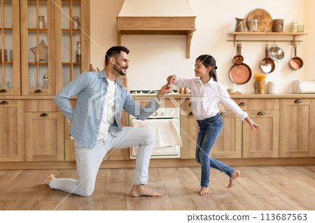Father and daughter dancing joyfully at home 113687563